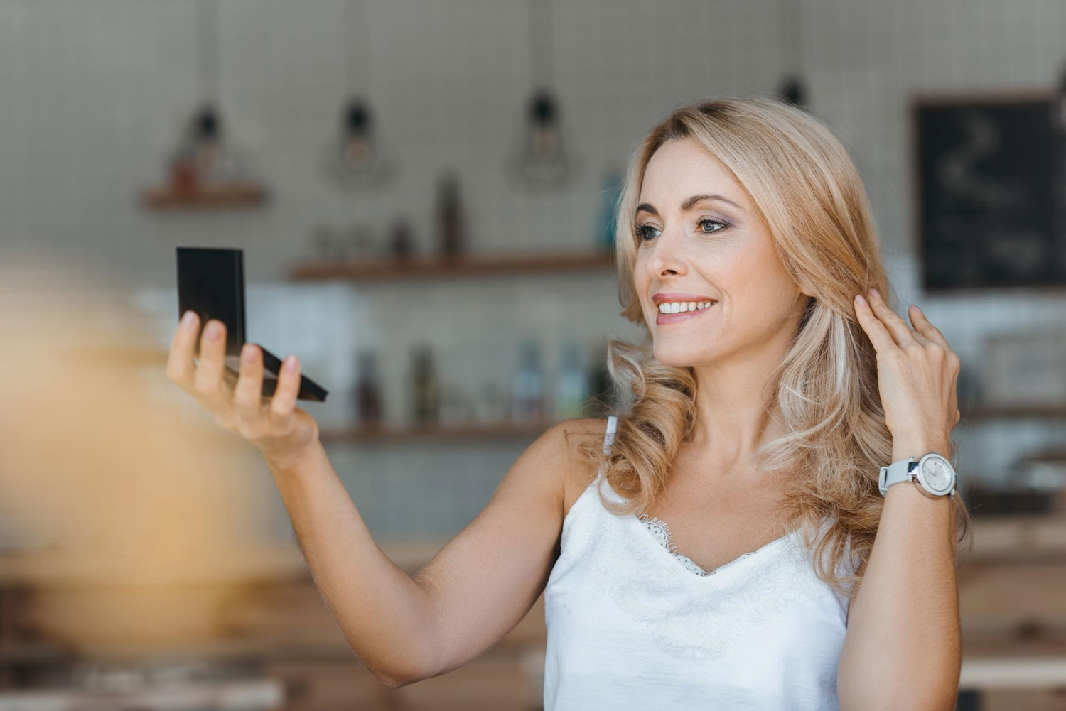 Blonde woman looking at her small mirror